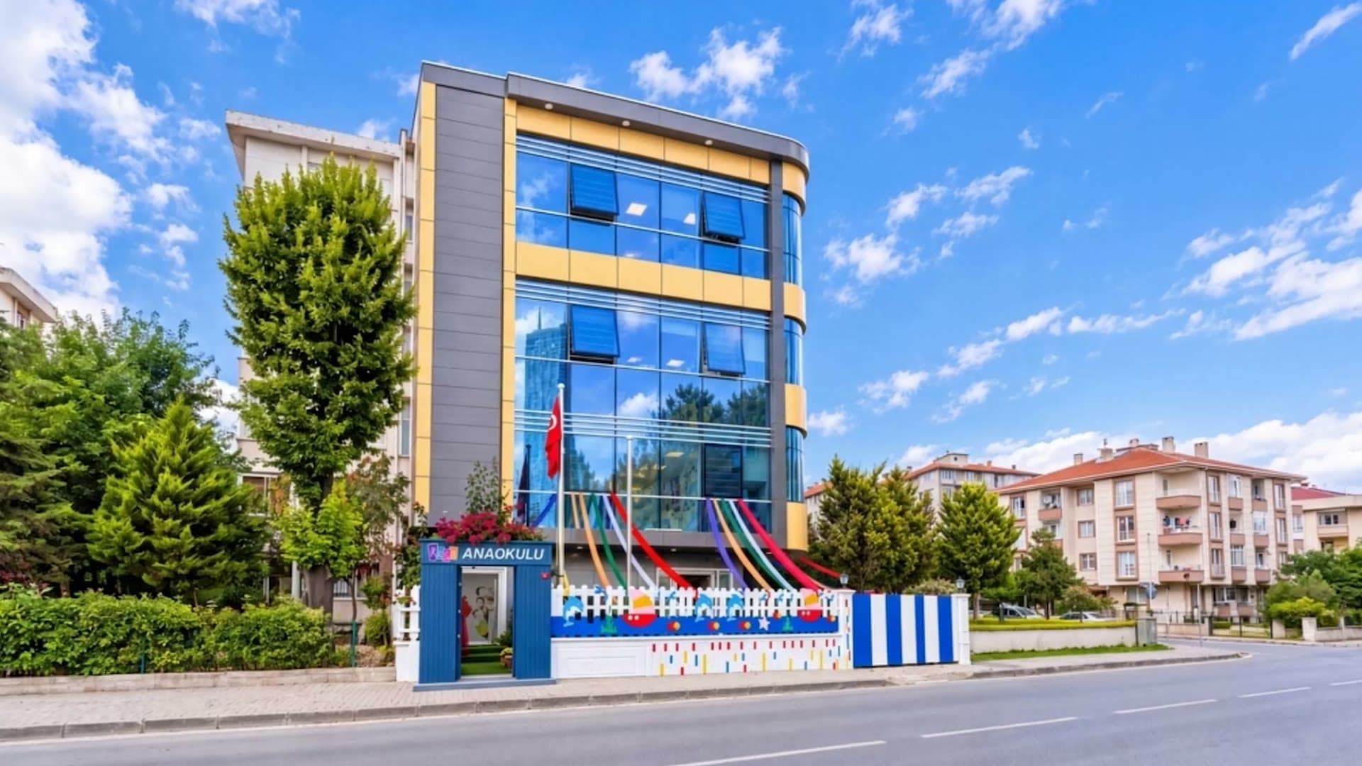 REGA Anaokulu Ümraniye binası, önünde ağaçlar ve renkli giriş çiti